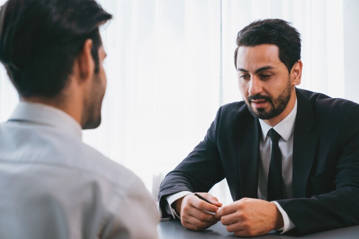 Man in suit sitting, looking nervous, job interview
