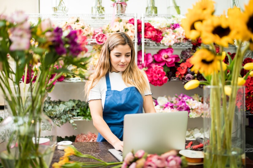 Woman working on laptop in flower shop