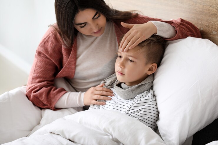 Mother sitting with sick child in bed