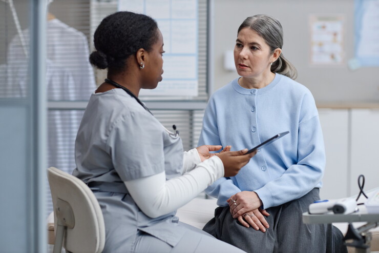 Woman speaking to nurse, doctor, sitting in office