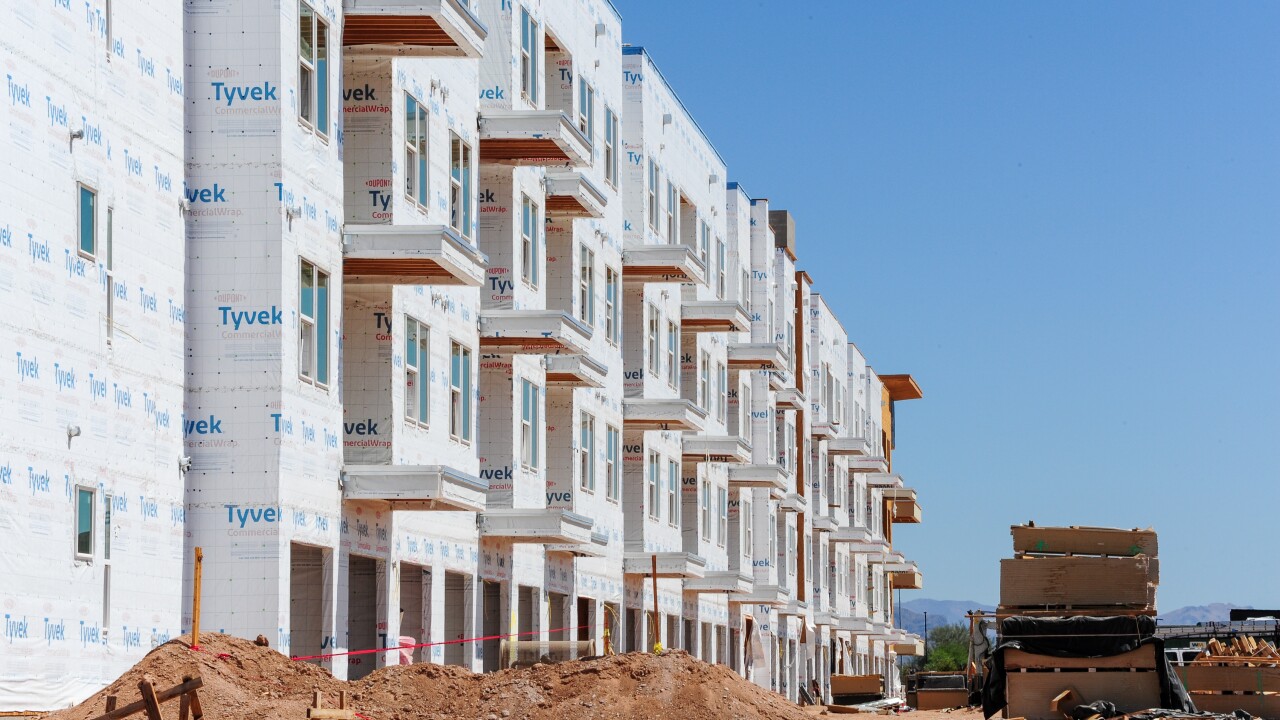 Exterior view of apartment buildings under construction, wrapped in high-density polyethylene material for air and water protection