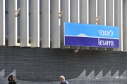 Pedestrians walk under Bank of Leumi sign