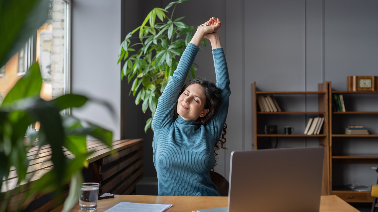 Woman stretching at desk, looking at peace