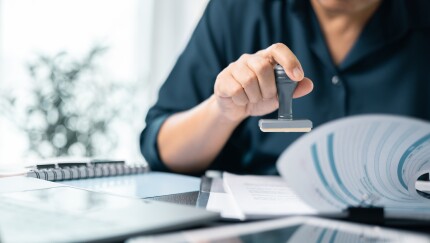 Banking officer stamped the document to approve the loan, finalizing the contract and solidifying the finance agreement, fundamental concept in business transactions. approve, loan, stamp, business.