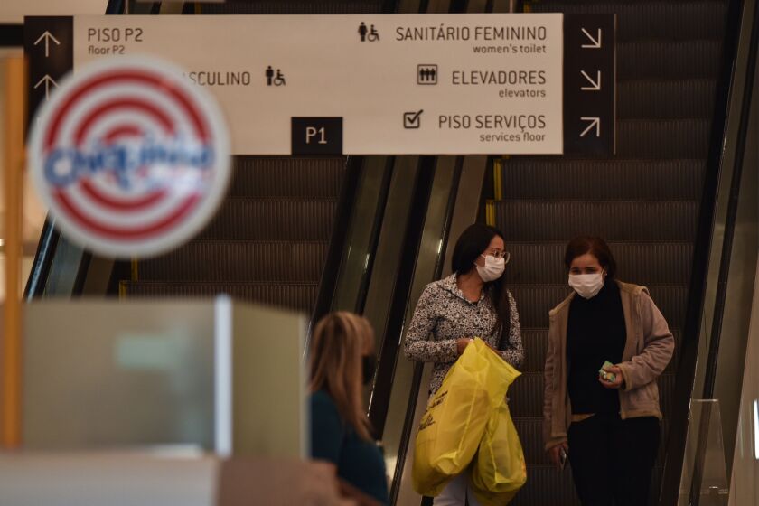 Shoppers wearing protective masks take an escalator in the Patio Brasil shopping mall in Brasilia, Brazil.