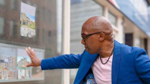 Man looks at real estate listings outside store in city during daytime