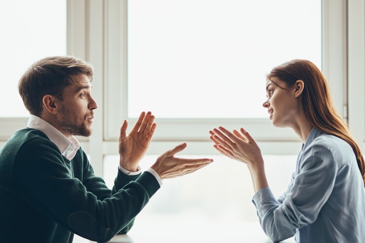 Two people, man and woman, having discussion; hands gesturing