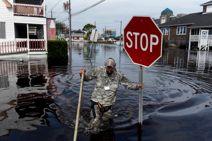 A member of a private critical crisis search and rescue team holds a stop sign as he wades through floodwaters after Hurricane Florence hit in Carolina Beach, North Carolina, U.S., on Monday, Sept. 17, 2018.