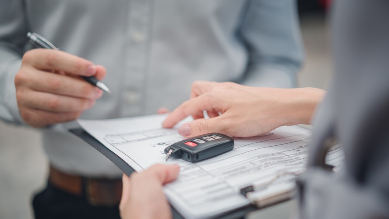 New owner signing for car keys for a new car.