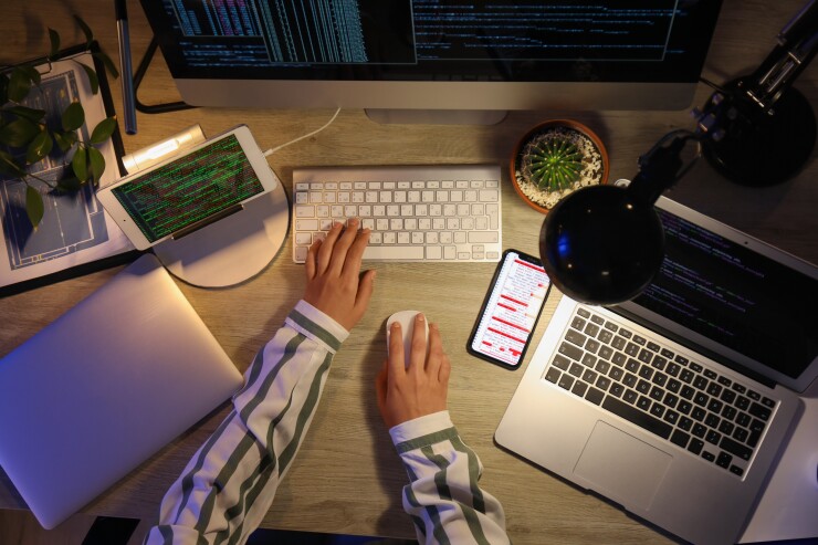 A person sitting at a desk typing with a laptop and a tablet.