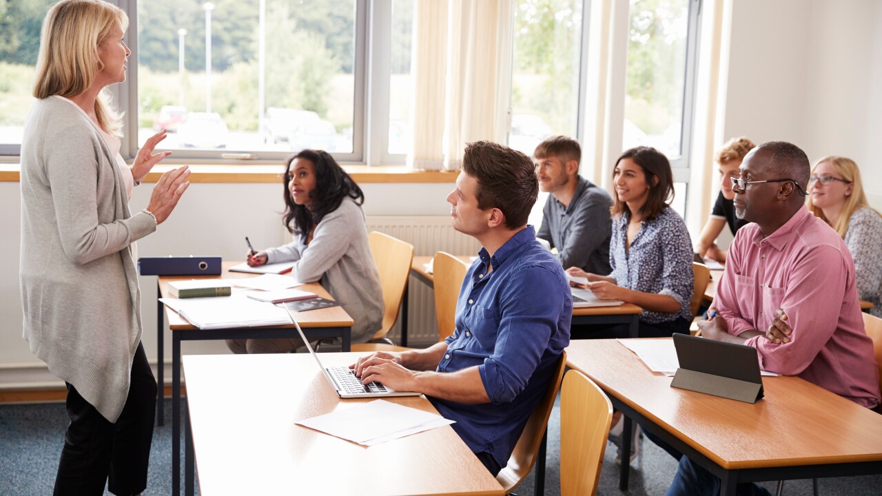 Adults sitting in classroom, instructor standing in front, speaking