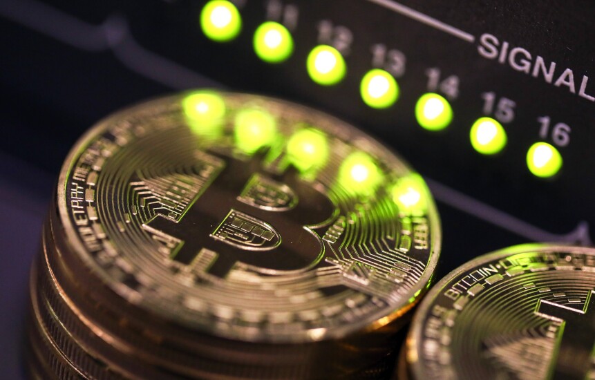 Stacks of bitcoins sit near green lights on a data cable terminal.