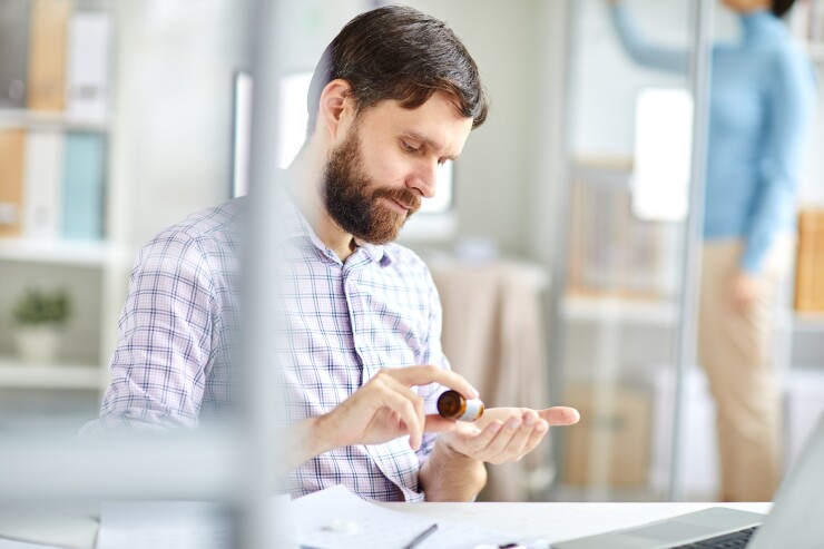 Man taking pills sitting at desk