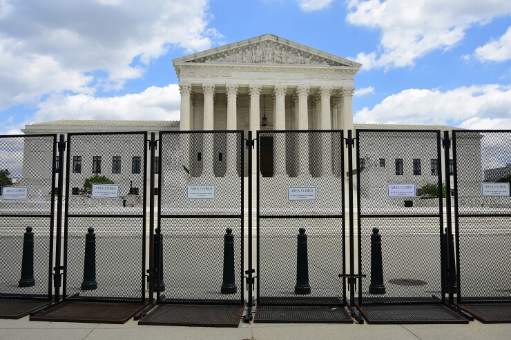 The exterior of the Supreme Court building guarded by a fence.