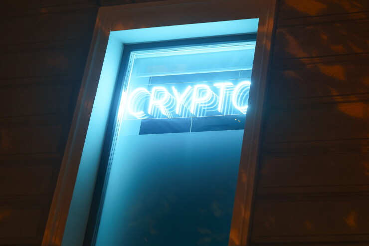 A neon sign reading "Crypto" and a euro currency symbol at a cryptocurrency exchange bureau in Riga, Latvia
