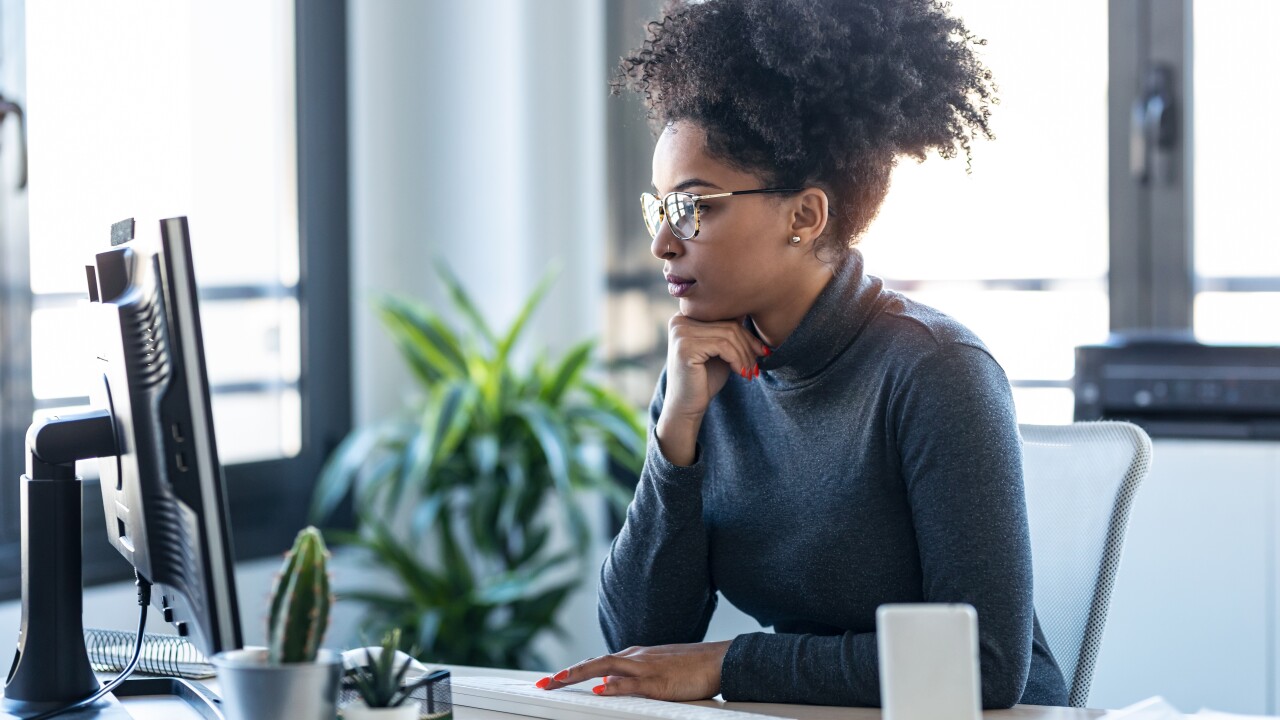 A woman at her desk, focused on her desktop.