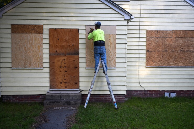 A man secures plywood to protect a window of a property ahead of Hurricane Florence in Greenville, North Carolina, U.S., on Wednesday, Sept. 12, 2018. Hurricane Florence is slowing as it advances upon the U.S. Southeast, promising "disaster" for residents near the Carolina coast. Photographer: Callaghan O'Hare/Bloomberg
