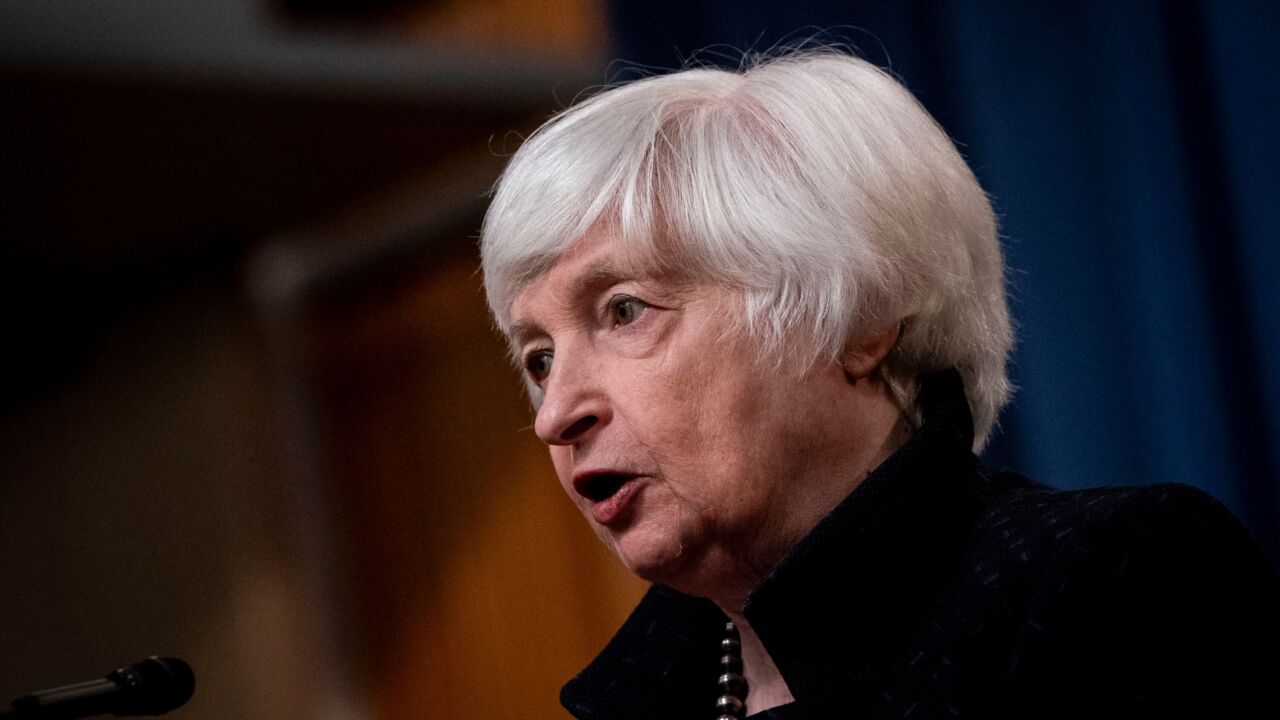 U.S. Treasury Secretary Janet Yellen speaking into a microphone, the background is blurred.