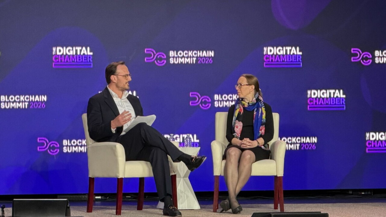 A man in a suit gestures with papers to a woman on stage at the Digital Chamber Blockchain Summit 2026.