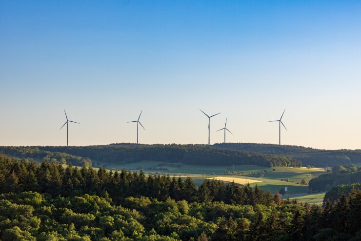 Wind turbines in a green field against a blue sky in Germany.