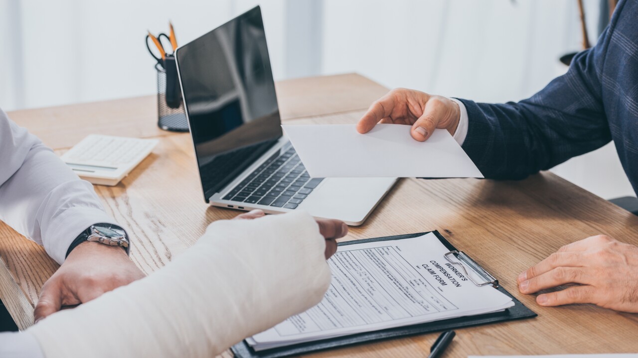 A person handing a paper to another person who has a cast on their right arm.