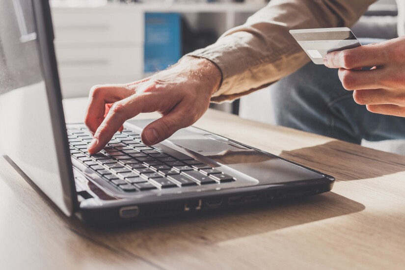 Man enters his bank card details to pay online or other financial transactions