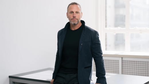 Propel Holdings CEO Clive Kinross leans against table in well-lit room for a headshot.