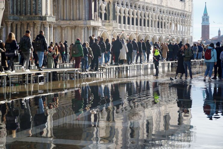 Tourists walks on raised walkways over floodwater in St. Marks Square in Venice, Italy, on Saturday, Nov. 26, 2022. The frequency of flooding, known as “acqua alta,” has been increasing steadily in Venice in recent years. Photographer: Andrea Merola/Bloomberg