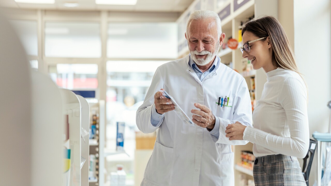 A pharmacist helps a customer in a sunlit store.