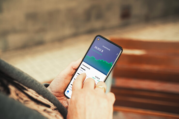 Investment Portfolio App Displayed on Smartphone Screen Outdoors. Personal finance, stock trading, fintech apps, and wealth management concept.