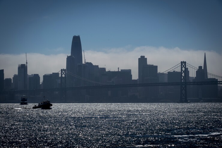 A boat passes in front of the San Francisco skyline as seen from the Port of Oakland.