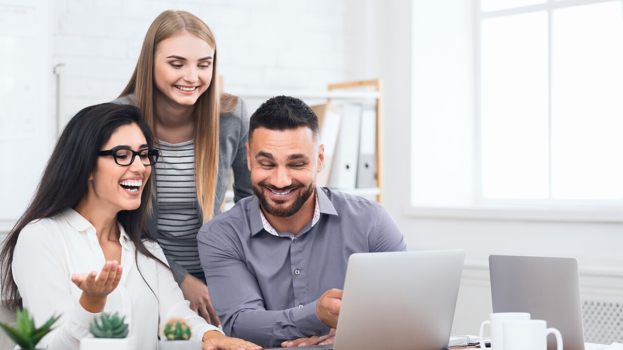 Three excited employees receiving good news on laptop