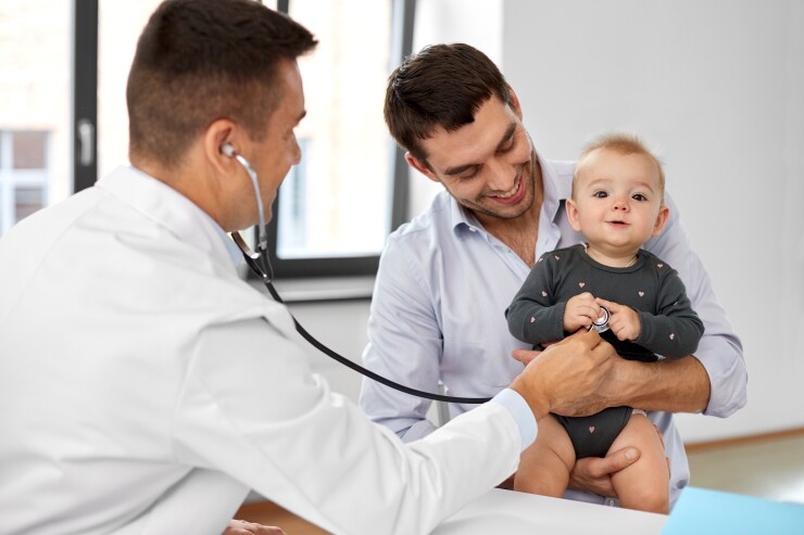 Dad and baby with doctor, doctor listening to baby's heart
