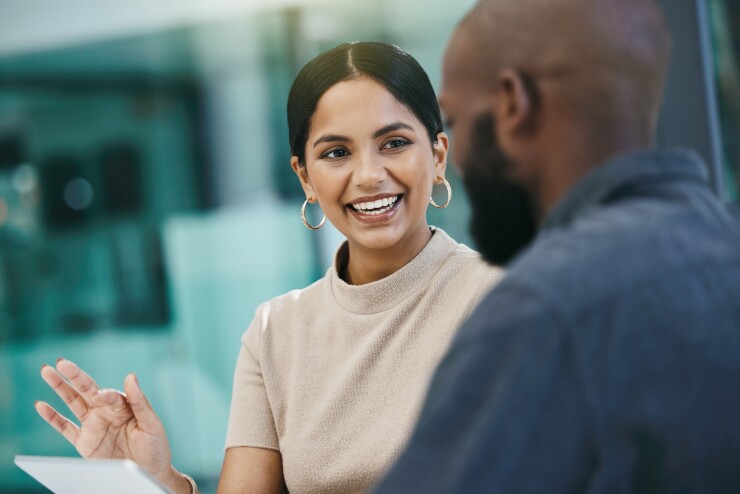 Woman talking to man, smiling, working together in office