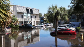 An area with cars and a building that is flooded.