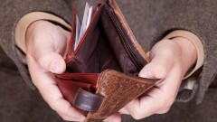 Broke businessman showing brown leather empty wallet. Business concept- finance and poor economy.