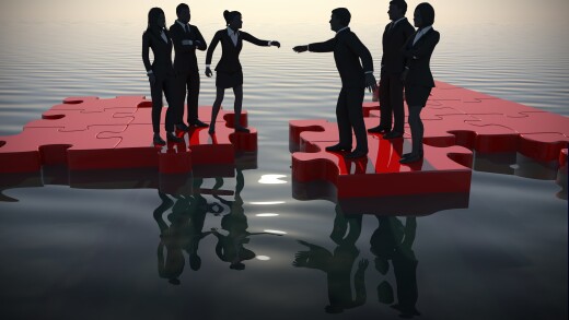 Putting the pieces together: Who stays and who goes? This is what ADOBE calls it: Two teams of managers merging on a jigsaw puzzle at dawn showing a partnership.