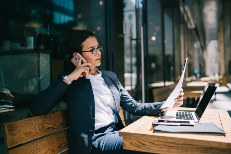 Busy woman calling on mobile phone during remote work.