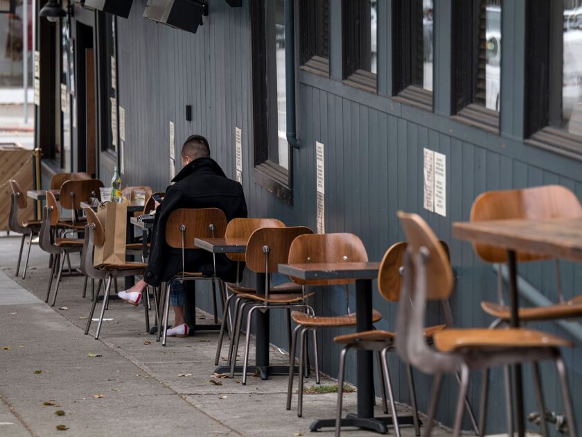 A person sits at a table outside of a restaurant in San Francisco, on Aug. 5.