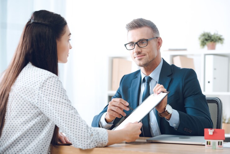A person handing another person a form on a clipboard