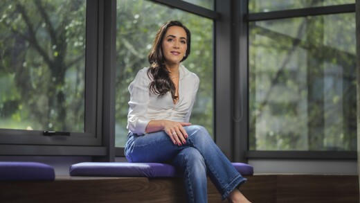 Nubank co-founder and U.S. CEO Cristina Junqueira sits on a purple cushioned bench and poses for a headshot.