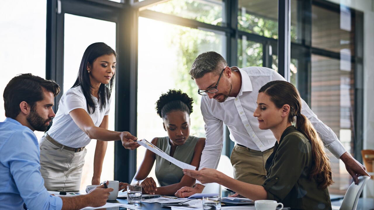 Employees working together around table, sitting, standing
