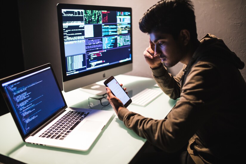 Man sitting at a desk staring at computer code.