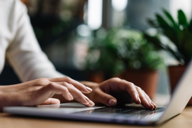 A closeup of a person's hands typing on a laptop