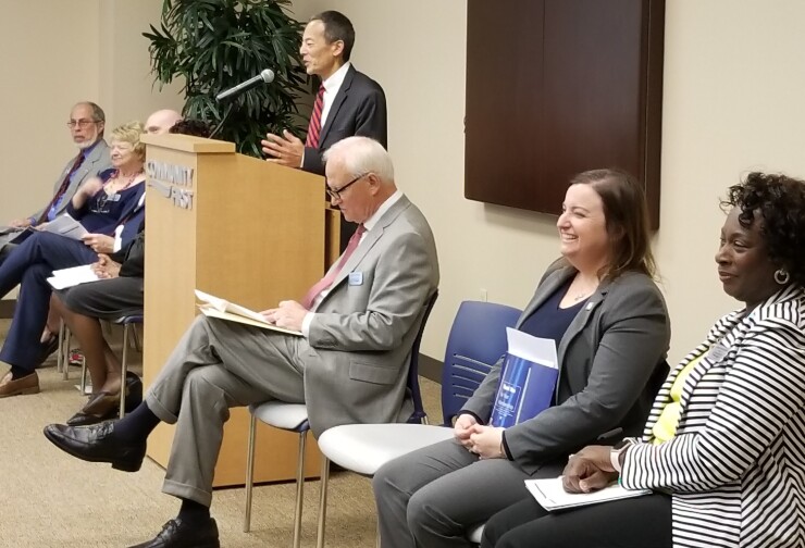 John Hirabayashi, CEO and president of Community First Credit Union, speaks at the CU's annual meeting. Foreground: Board chair William Permenter, board member Malinda Prudencio and board member Brenda Simmons-Hutchins. Additional board members on the other side.