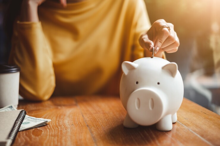 Person putting money in piggy bank, saving, retirement