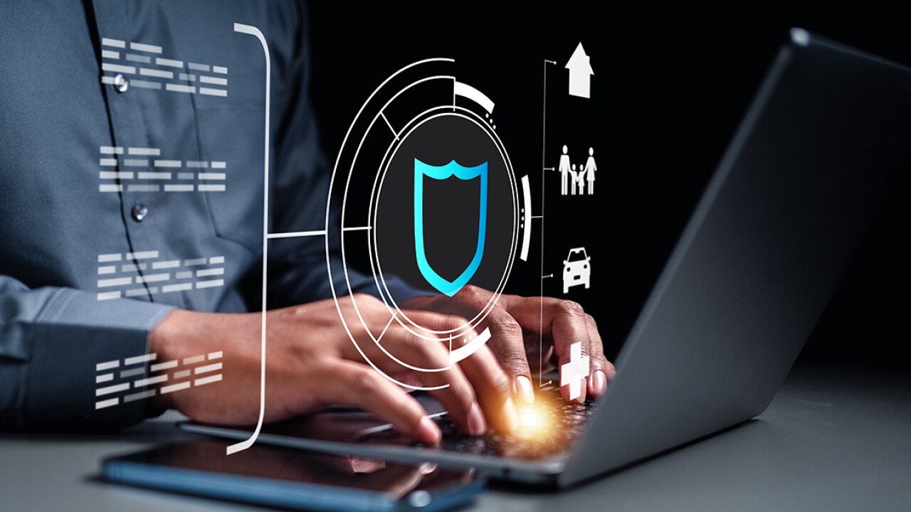 man typing on laptop, behind projection of a shield, auto, home and other logos