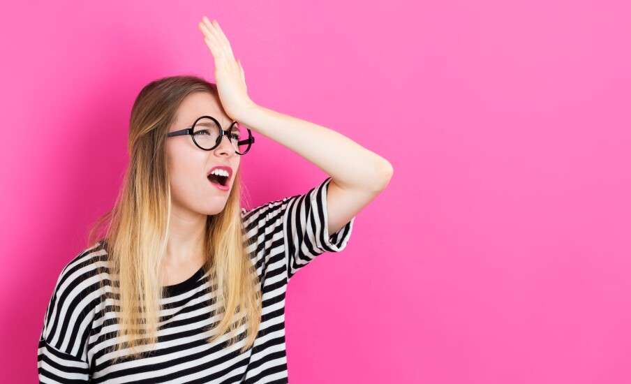 Young woman making a mistake on a pink background