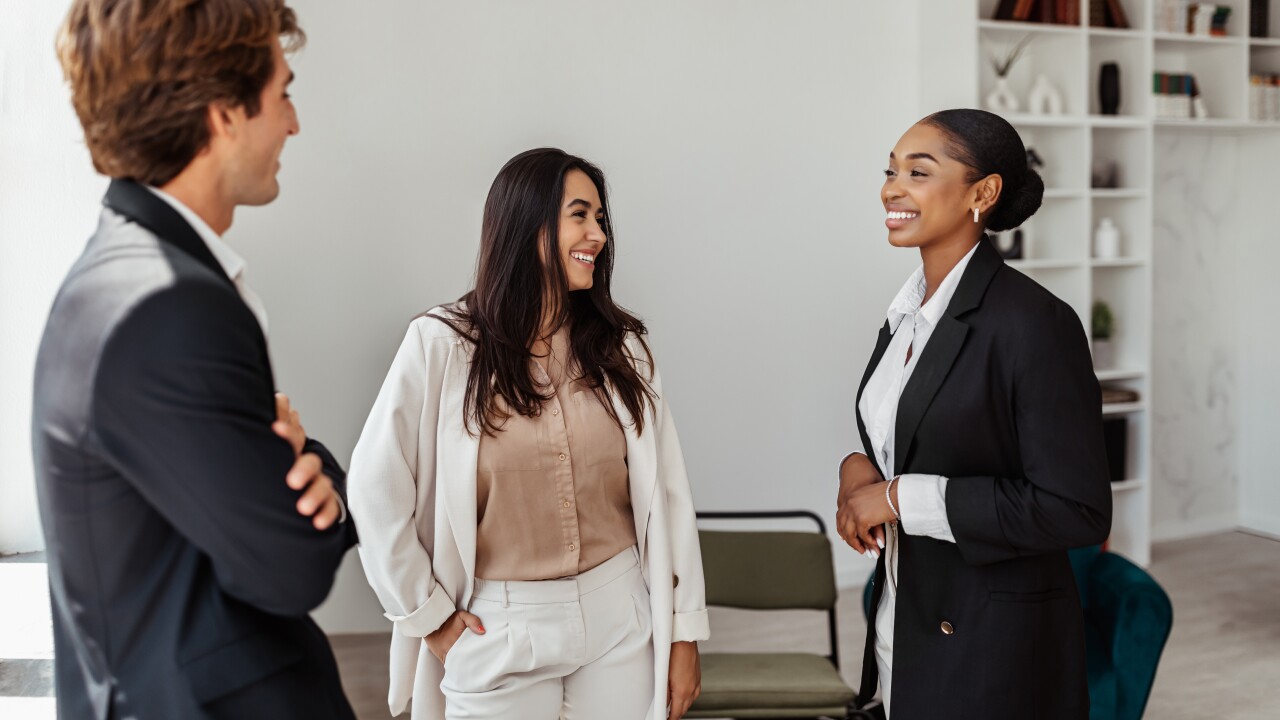 Three employees, standing, talking in office