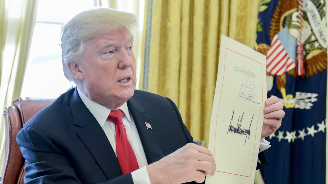 President Donald Trump holds up a tax-overhaul bill after singing it into law in the Oval Office.